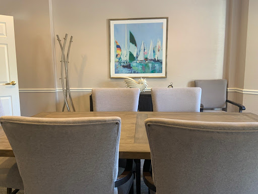 A modern conference room featuring a large table, comfortable chairs, and a colorful artwork on the wall.
