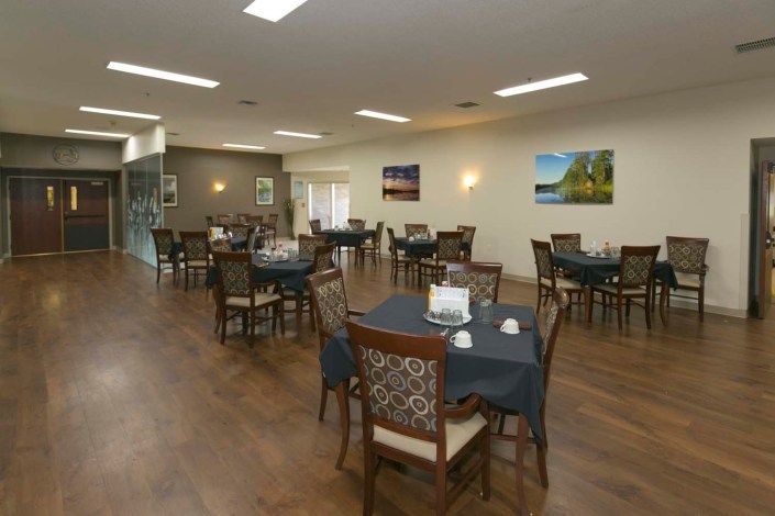 A spacious dining area with neatly arranged tables and chairs, adorned with wall art.