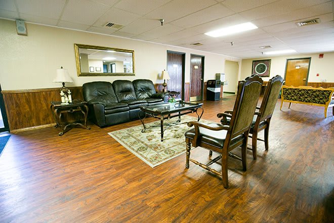 A cozy living room featuring a leather sofa, elegant chairs, and a coffee table on a hardwood floor.