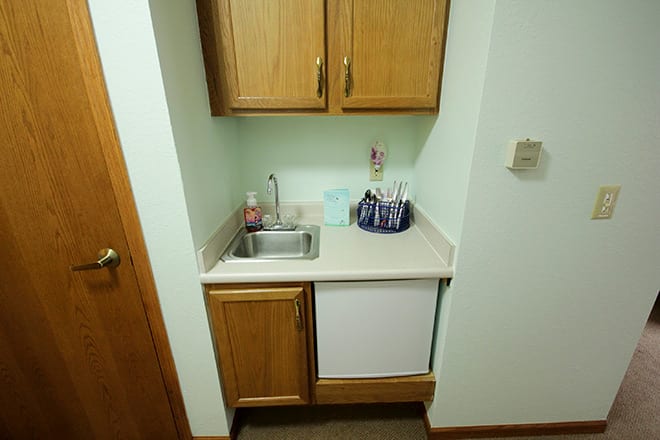 A compact kitchenette with a sink, cabinets, and countertop.