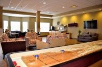 A spacious lounge area featuring comfortable seating and a shuffleboard table.