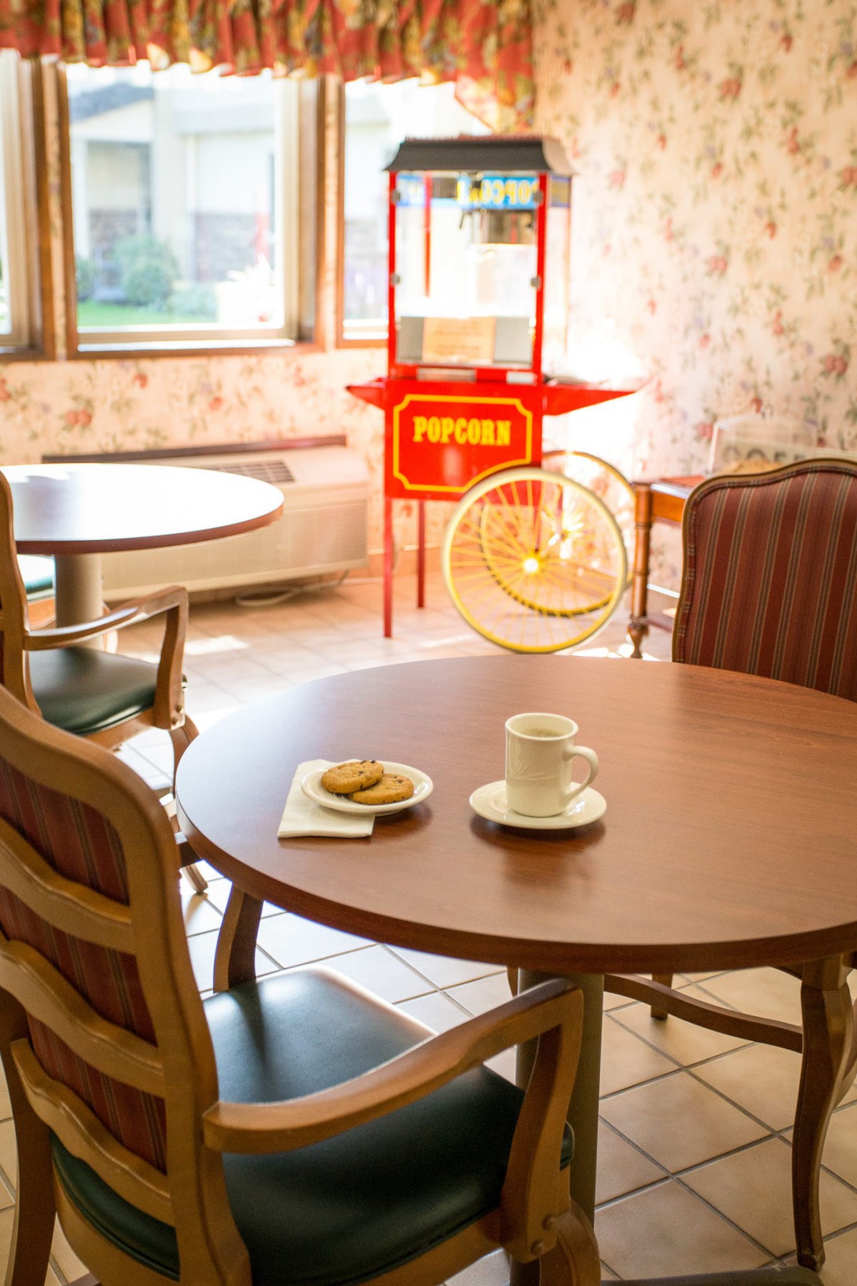 A cozy cafe interior with a table set for coffee and a popcorn machine in the background.