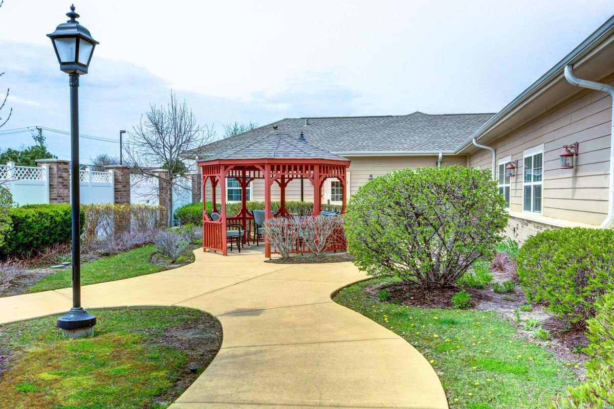 A landscaped garden with a winding pathway leading to a red gazebo.