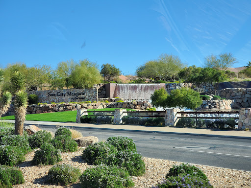 A serene park featuring a waterfall and lush greenery against a clear blue sky.