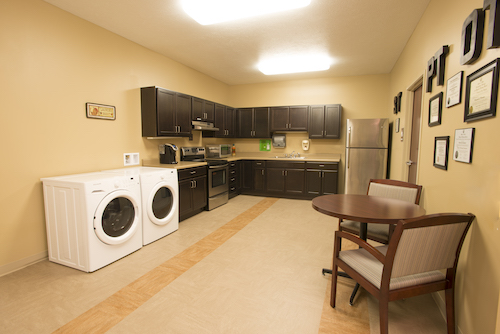 A modern kitchen featuring a laundry area with washing and drying machines, complemented by sleek cabinetry and a dining space.