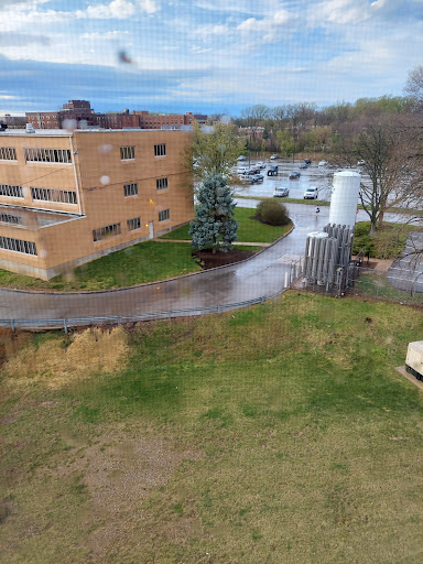 An aerial view of a building surrounded by greenery and a parking lot.