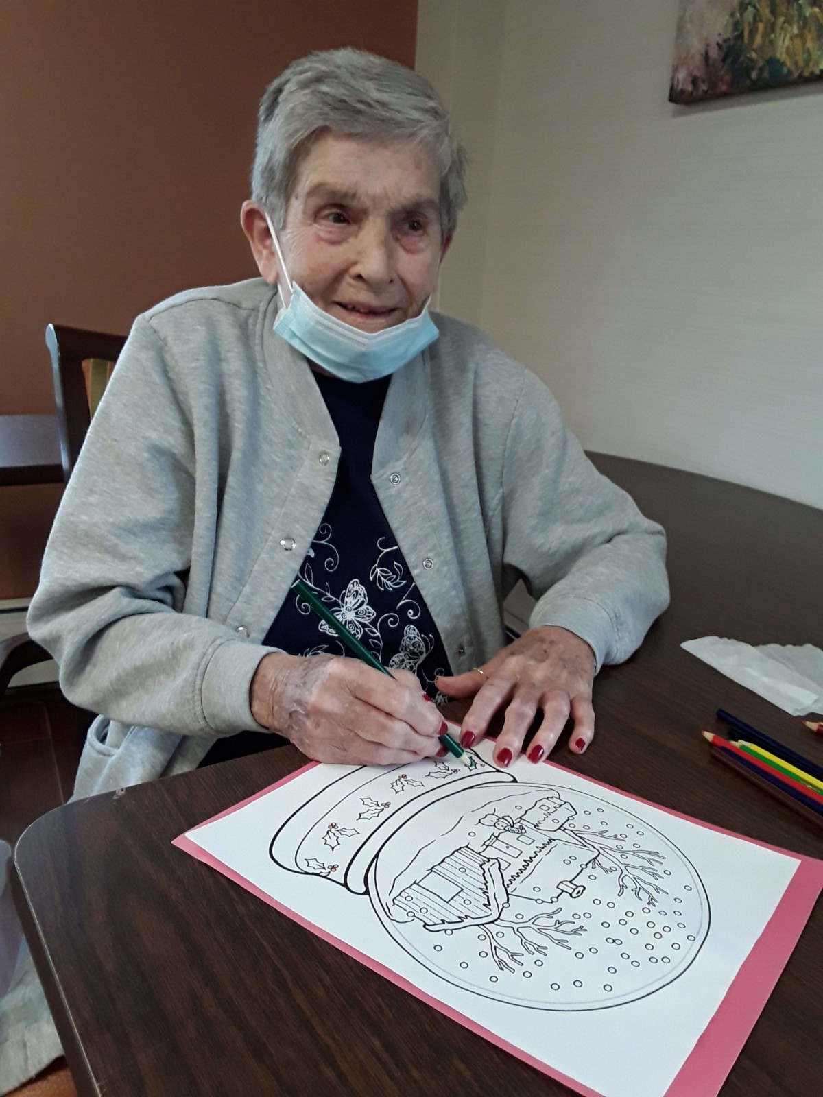 An elderly woman engaged in coloring a picture at a table.
