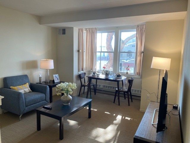 A cozy living room with a sofa, coffee table, and a dining area by the window.