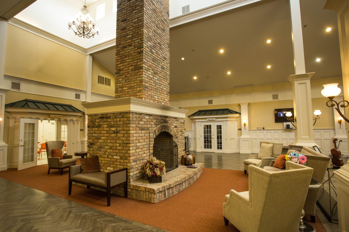 A cozy lobby with a central brick fireplace and comfortable seating.