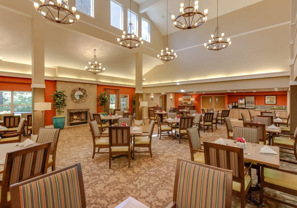 A spacious dining area with elegant chandeliers and neatly arranged tables and chairs.