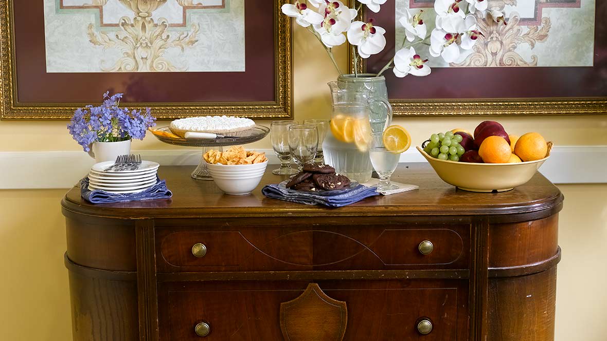 A beautifully arranged table with snacks, fruits, cookies, and a pitcher of lemonade.