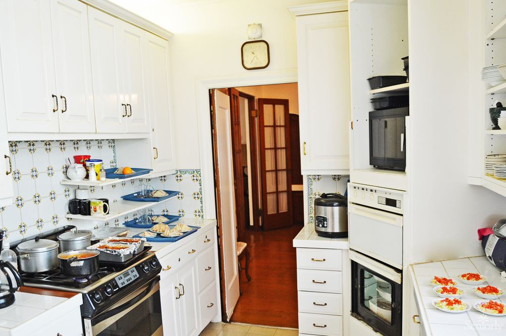 A cozy kitchen with white cabinets, equipped with modern appliances including an oven, microwave, and rice cooker.