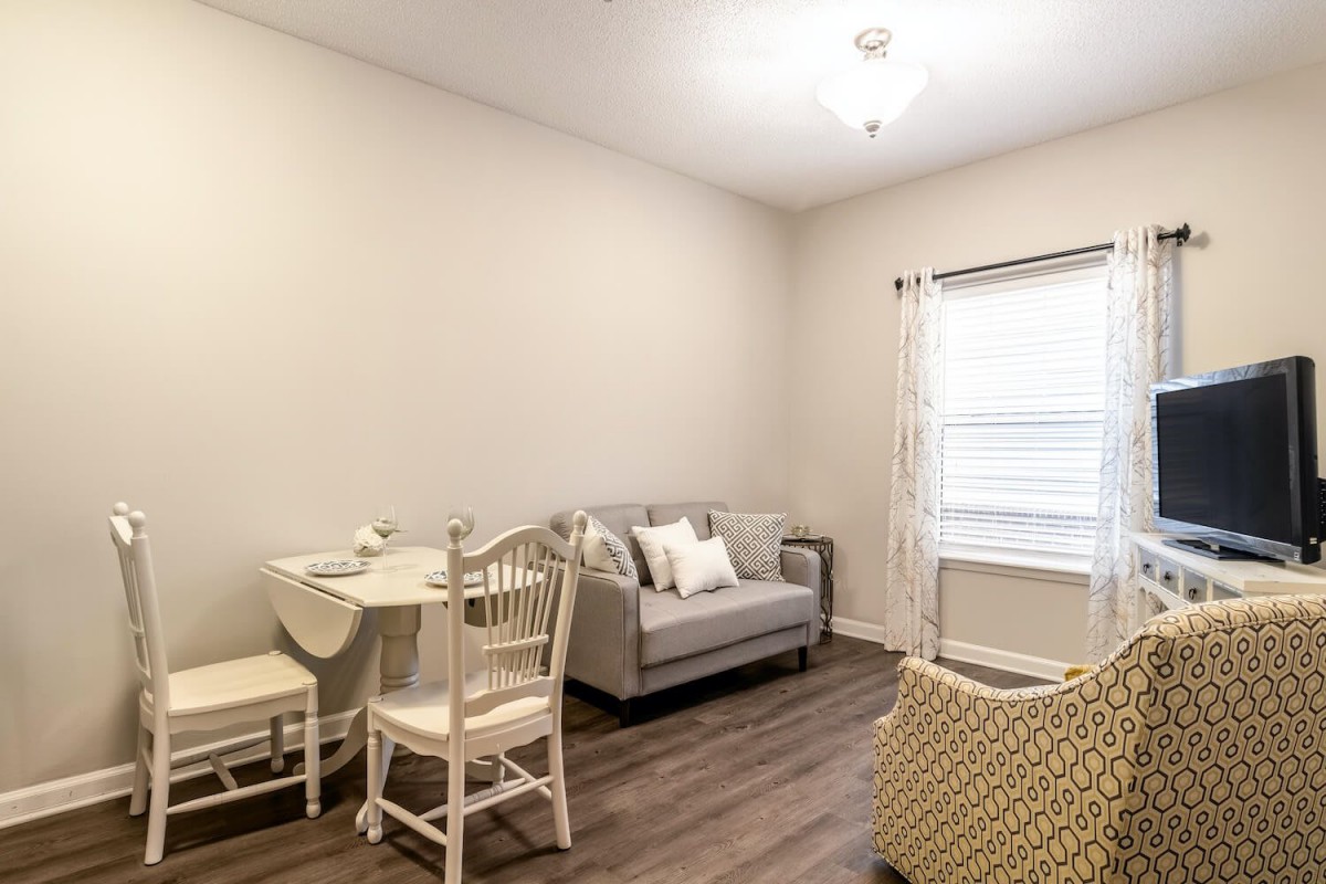A minimalist living room with neutral colors, featuring a cozy sofa, dining table, and chairs.
