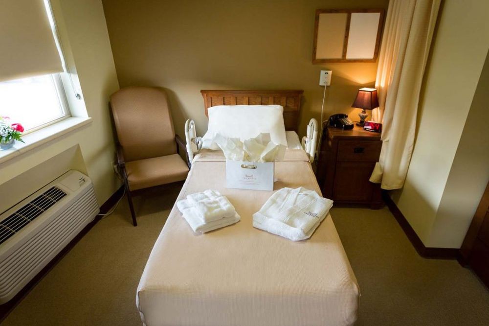 A neatly arranged hospital room with a bed, chair, and bedside table.