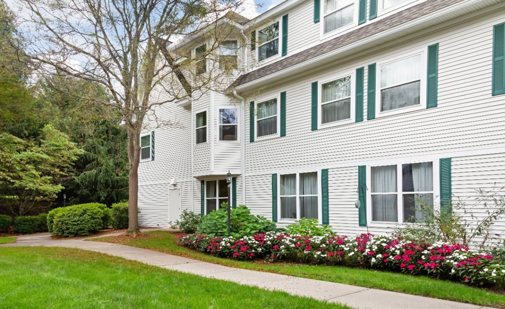 A well-maintained apartment building with lush green landscaping and vibrant flowers.