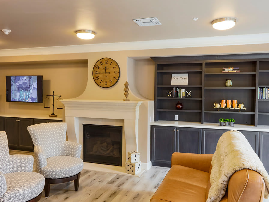 A cozy living room featuring a fireplace, comfortable seating, and a wall-mounted clock.