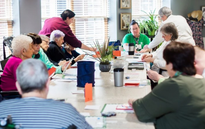 A group of people engaged in a community meeting around a large table.