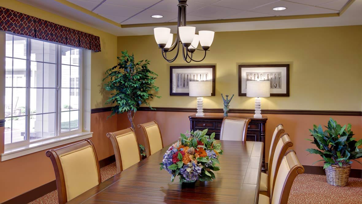A well-decorated dining room with a wooden table, cushioned chairs, and elegant lighting.