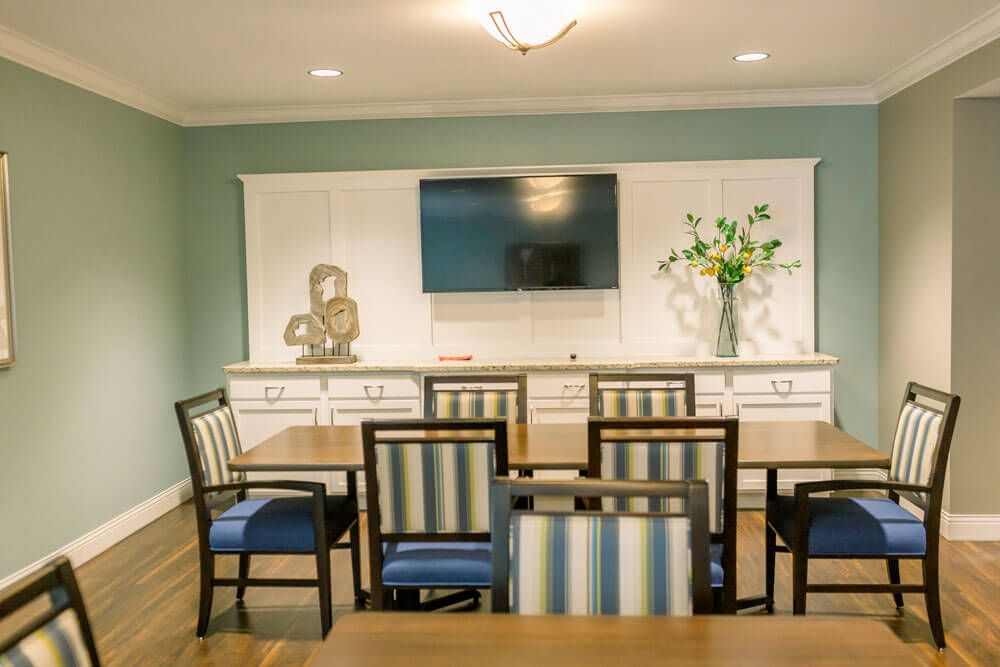 A modern dining room with striped chairs, a mounted television, and decorative elements.
