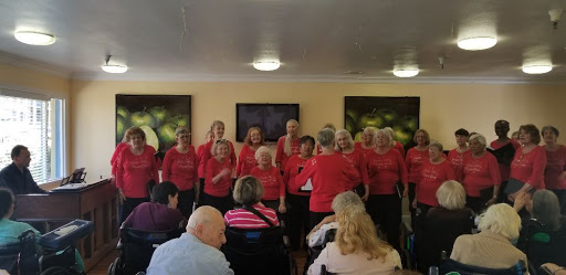 A lively choir performance by a group of enthusiastic seniors in red shirts.