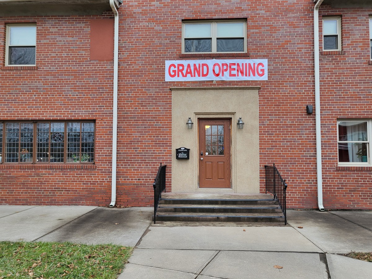 A brick building with a 'Grand Opening' sign above the entrance.