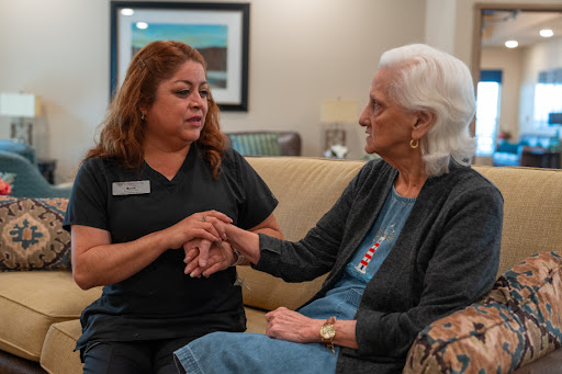 A caregiver engages in a supportive conversation with an elderly resident, emphasizing compassion and connection in healthcare.