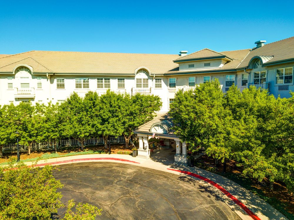 A large residential building with a circular driveway and surrounding trees.