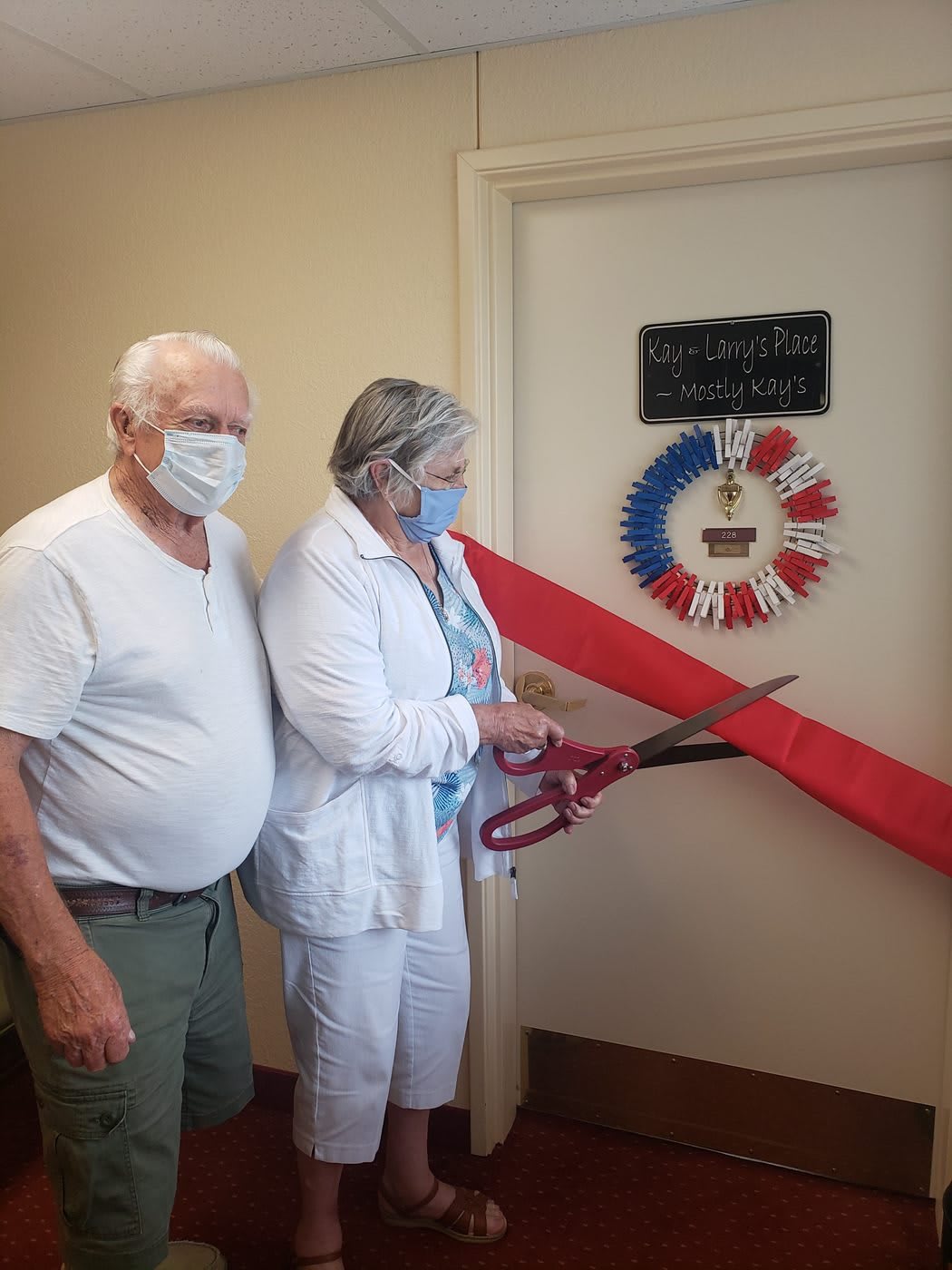 An elderly couple participates in a ribbon-cutting ceremony.