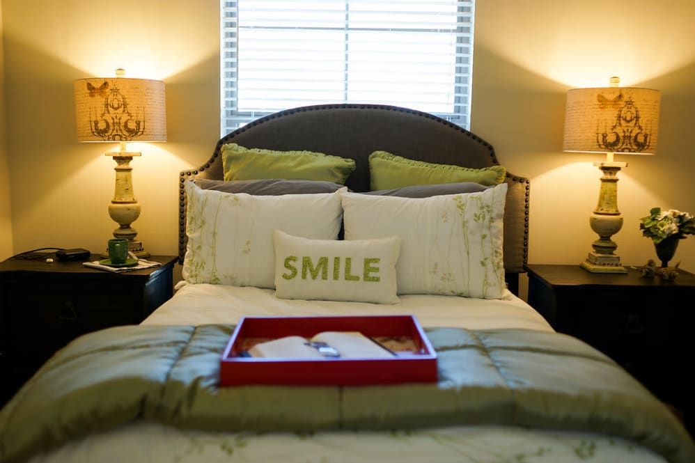 A cozy bedroom with decorative pillows and warm lighting.