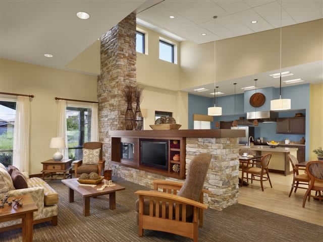 A cozy living room with a stone fireplace and rustic wooden furniture, featuring an open and inviting atmosphere.
