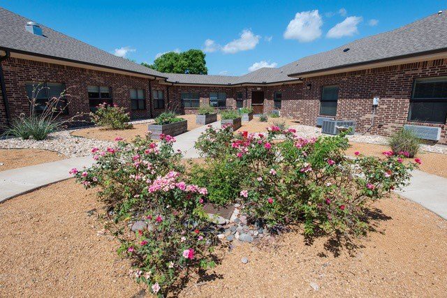 A beautifully landscaped courtyard with vibrant flowers and a brick building backdrop.
