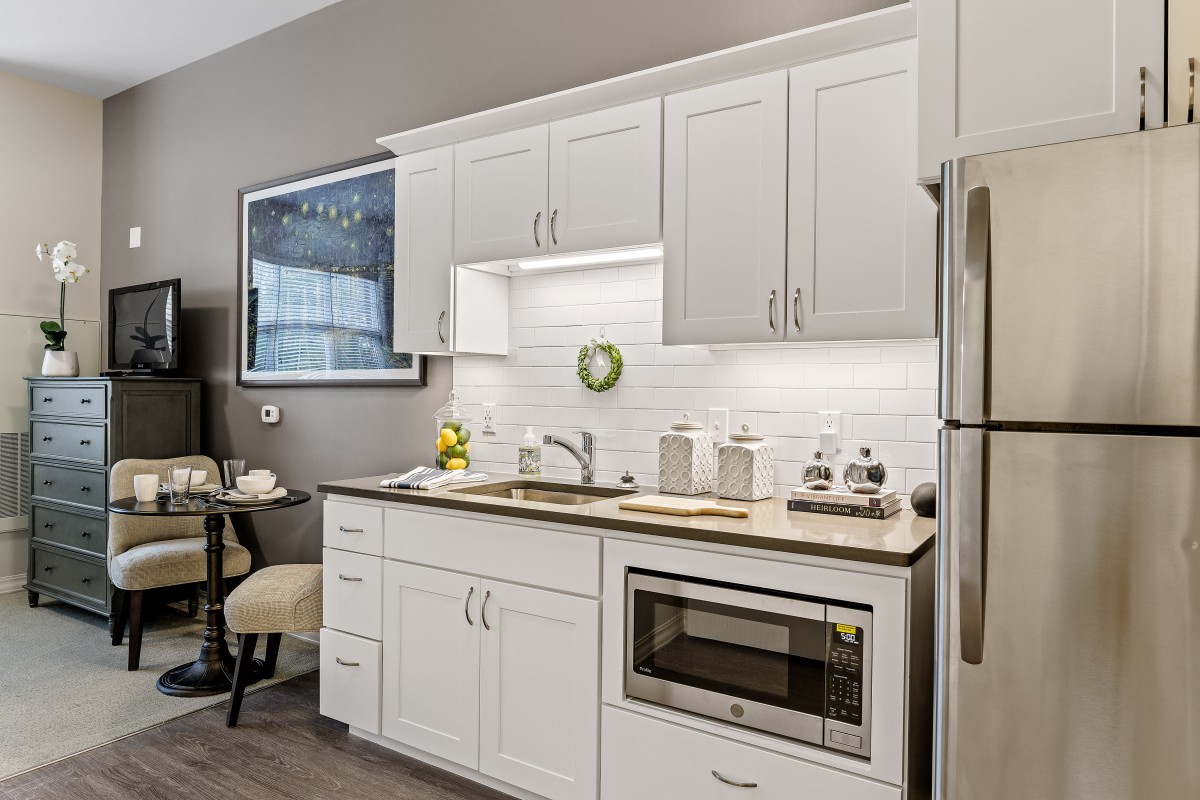 A modern kitchen with white cabinets, featuring a microwave and sleek countertop.