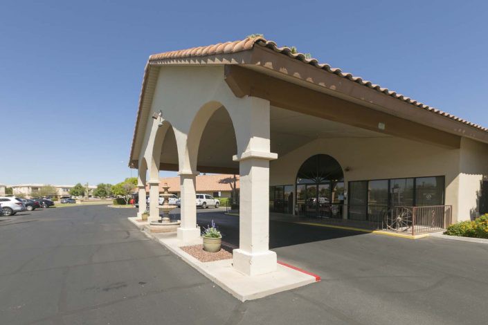 An outdoor view of a hotel entrance with arches and a tiled roof.