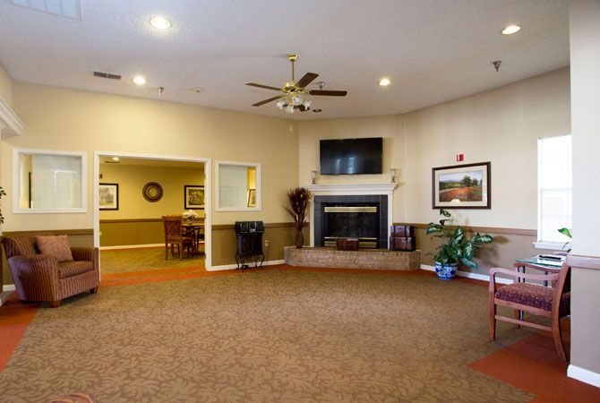 A cozy living room with a fireplace, television, and ceiling fan.