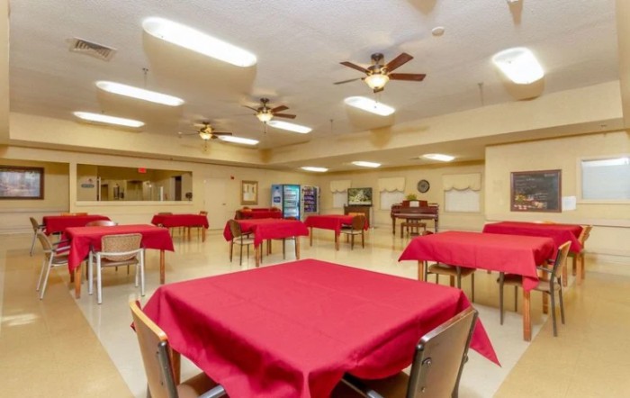 A spacious dining area with red tablecloths and ceiling fans.