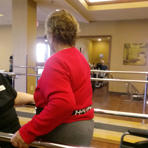 An elderly individual participating in a physical therapy session, using support bars for assistance.