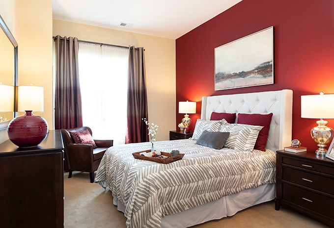 A cozy bedroom with a red accent wall, plush bedding, and stylish decor.