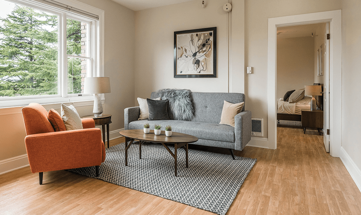 A cozy living room with a gray sofa, an orange armchair, and a modern coffee table.