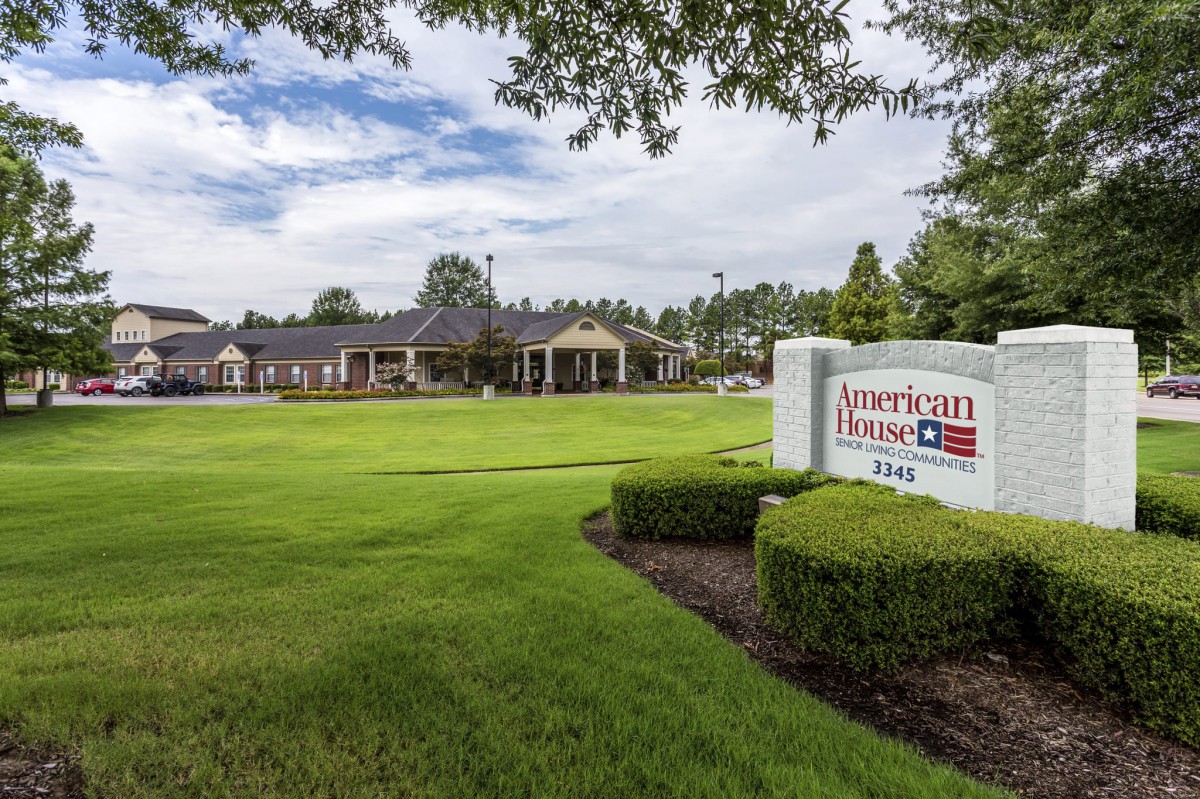 A landscaped area with a building and a prominent sign under a cloudy sky.