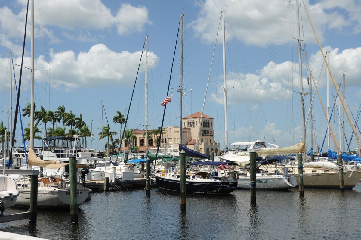 A scenic view of a marina with boats docked under a partly cloudy sky.