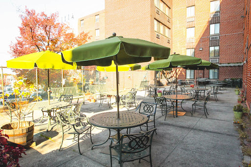 A cozy outdoor seating area with green umbrellas and tables, perfect for enjoying a sunny day.