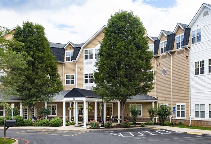 A residential building with a welcoming entrance surrounded by trees and a parking area.