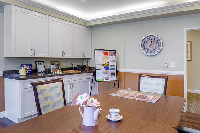 A neatly arranged kitchen with a wooden table set for tea.