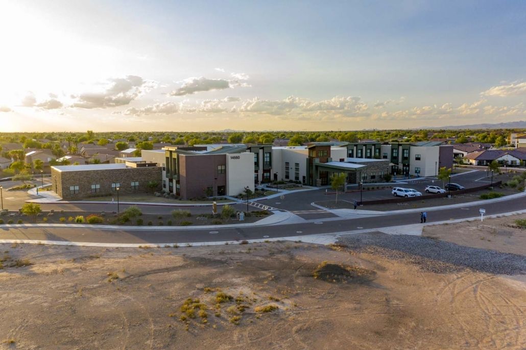 Aerial view of a modern building complex against a desert backdrop at sunset.