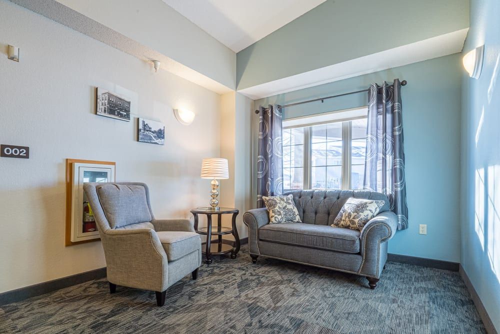 A cozy living room with a sofa and armchair near a large window, featuring stylish decor.