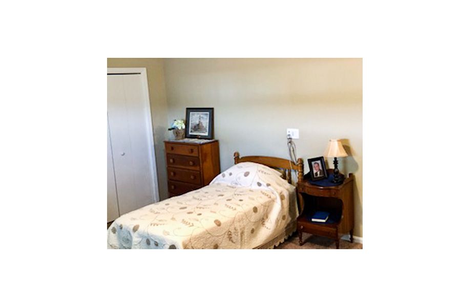 A cozy bedroom with a single bed, nightstand, and dresser.