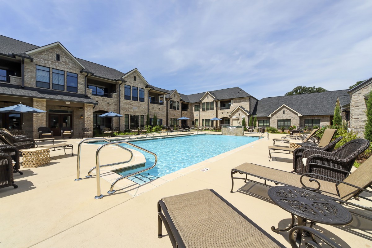 A serene residential complex featuring an outdoor swimming pool and sun loungers.