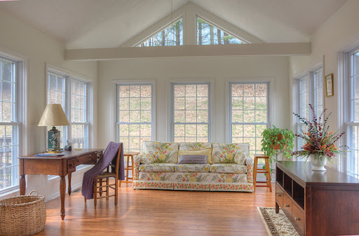 A bright and inviting living room featuring large windows, a comfortable sofa, and warm wooden flooring.