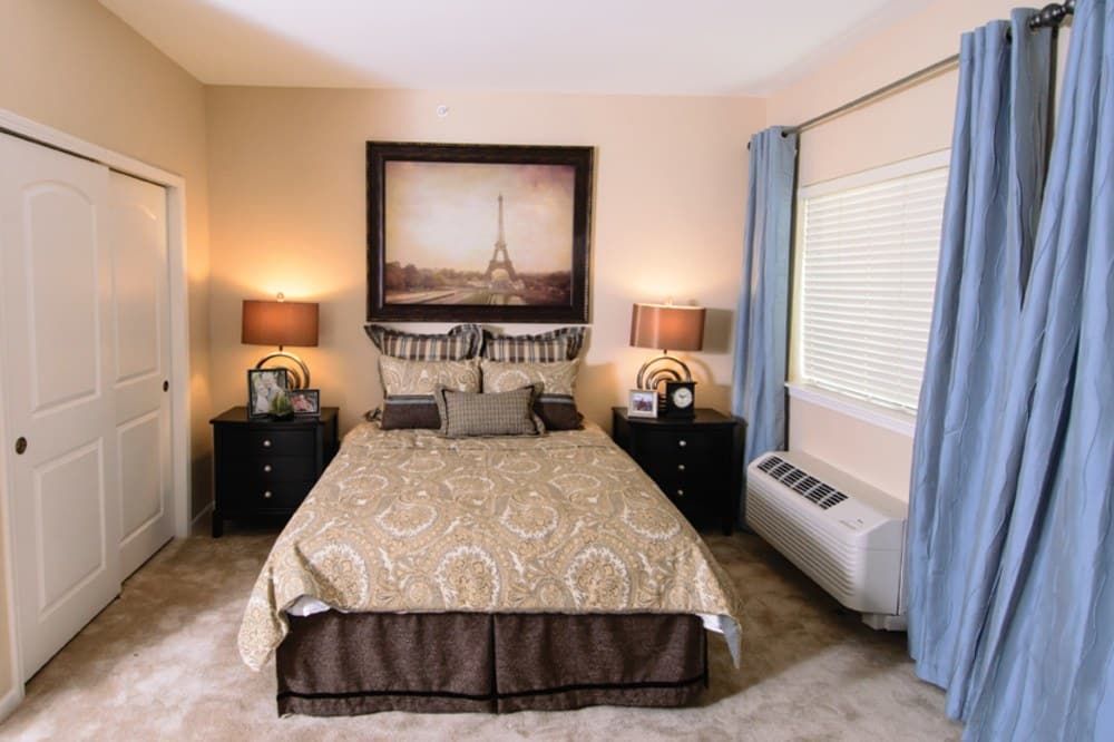 A cozy, well-decorated bedroom with elegant bedding and framed artwork above the bed.