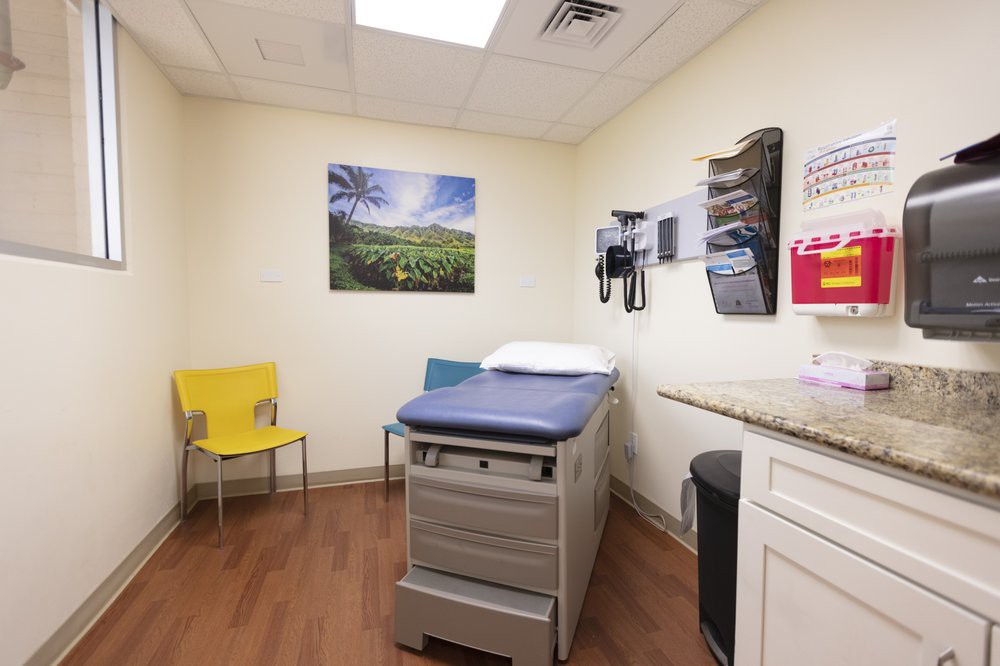 A clean and organized doctor's examination room with medical equipment and seating.